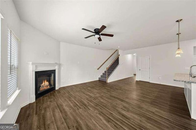 unfurnished living room with dark wood-type flooring and ceiling fan