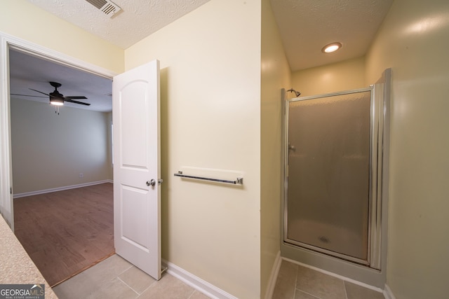 bathroom with tile patterned flooring, an enclosed shower, and a textured ceiling