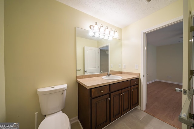 bathroom featuring vanity, tile patterned floors, a textured ceiling, and toilet