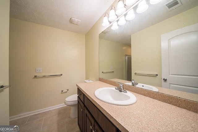 bathroom with tile patterned flooring, vanity, a textured ceiling, toilet, and walk in shower