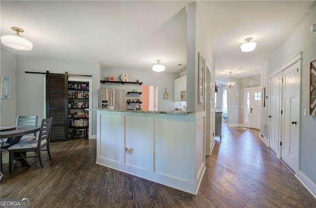 kitchen with dark wood-type flooring, a barn door, stainless steel fridge with ice dispenser, and white cabinets