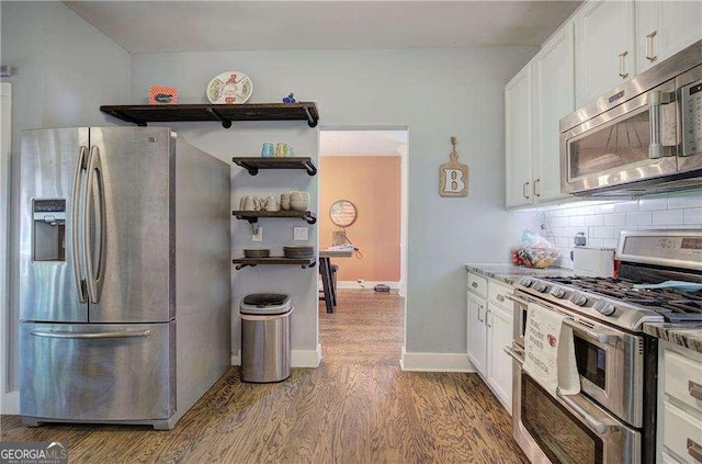 kitchen with appliances with stainless steel finishes, hardwood / wood-style floors, white cabinets, and backsplash