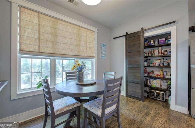 dining room featuring dark hardwood / wood-style floors, plenty of natural light, and a barn door