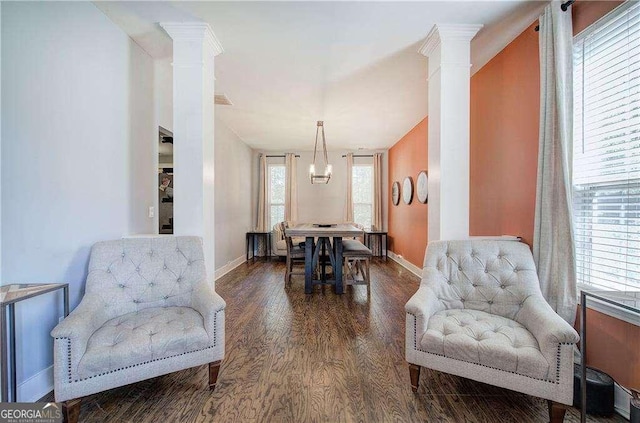 dining area featuring dark hardwood / wood-style flooring, decorative columns, and a notable chandelier