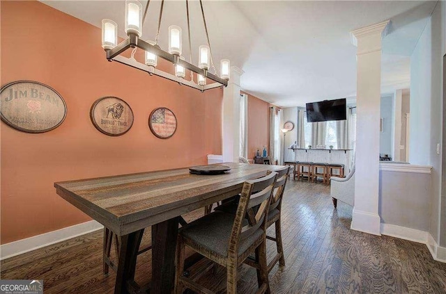 dining space featuring dark wood-type flooring and decorative columns