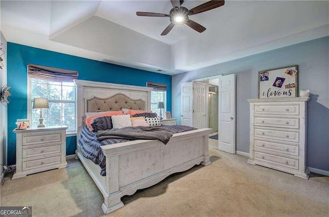 bedroom featuring ceiling fan, light colored carpet, lofted ceiling, and a raised ceiling