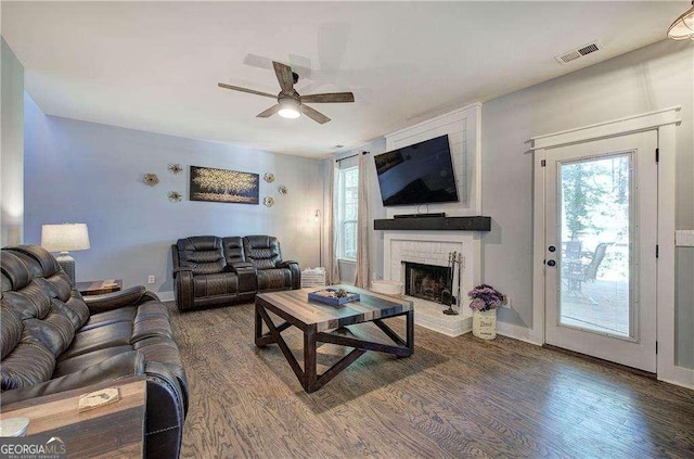 living room with dark hardwood / wood-style flooring, a brick fireplace, a healthy amount of sunlight, and ceiling fan