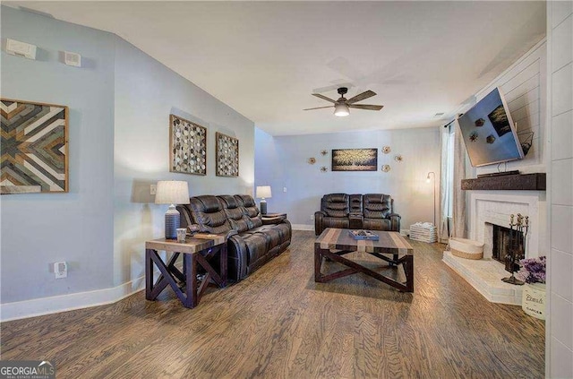 living room with ceiling fan, hardwood / wood-style floors, and a brick fireplace