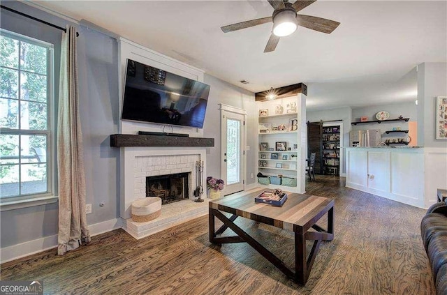 living room with dark wood-type flooring, a brick fireplace, and a wealth of natural light