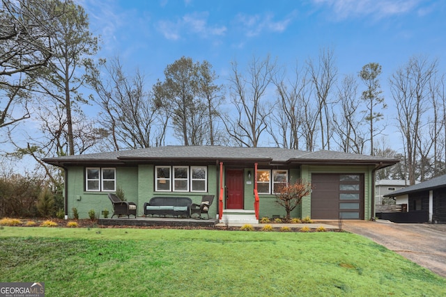 view of front of house featuring an attached garage, a front yard, concrete driveway, and brick siding