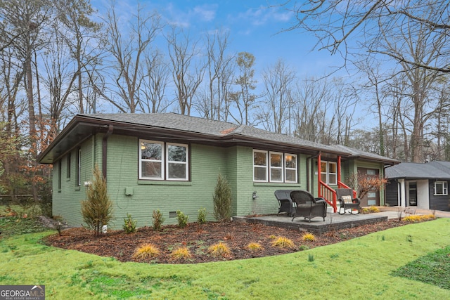 view of front of property with brick siding, roof with shingles, crawl space, a patio area, and a front yard