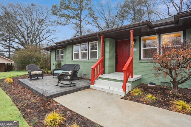 property entrance featuring crawl space, brick siding, a patio, and an outdoor living space