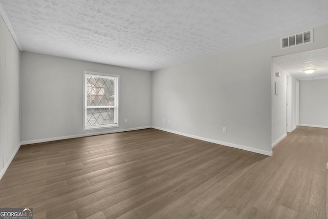 unfurnished room with hardwood / wood-style floors and a textured ceiling