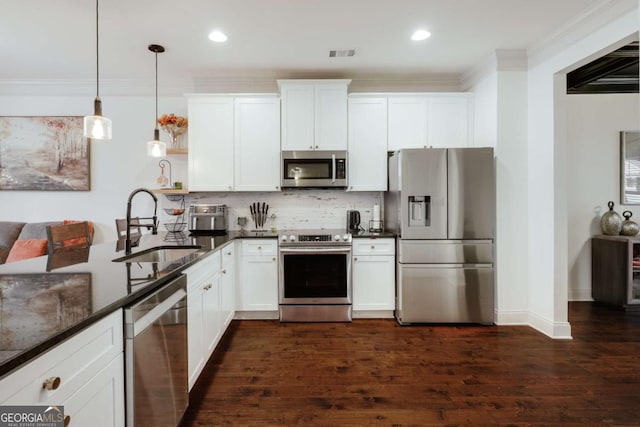 kitchen featuring stainless steel appliances, white cabinetry, sink, and decorative light fixtures