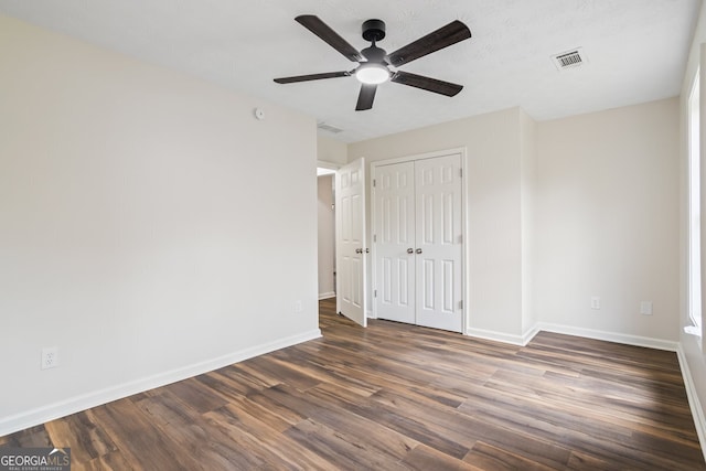 unfurnished bedroom featuring dark wood-type flooring, a closet, and ceiling fan