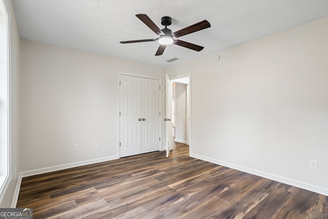 unfurnished bedroom with ceiling fan, dark wood-type flooring, a closet, and a textured ceiling