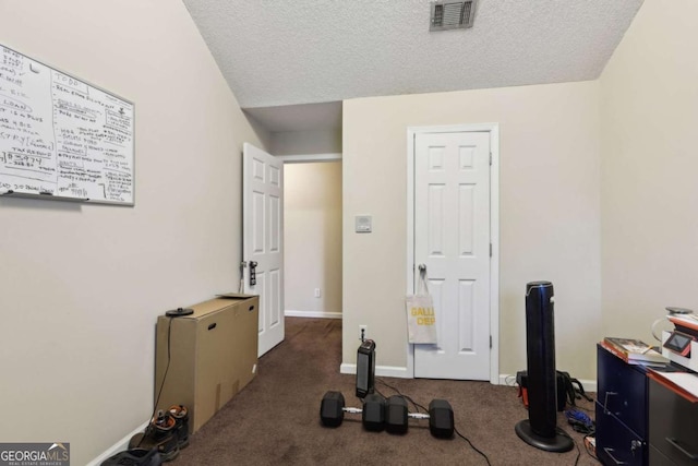 workout area featuring a textured ceiling and dark colored carpet