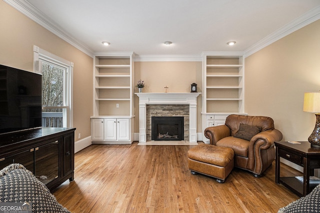 living area with crown molding, a fireplace, built in features, and wood finished floors