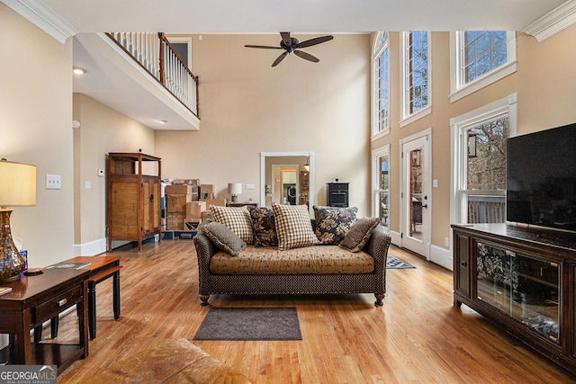 living room featuring a barn door, baseboards, ceiling fan, wood finished floors, and crown molding