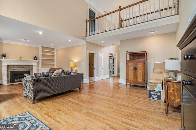 living area featuring baseboards, a fireplace, wood finished floors, and crown molding