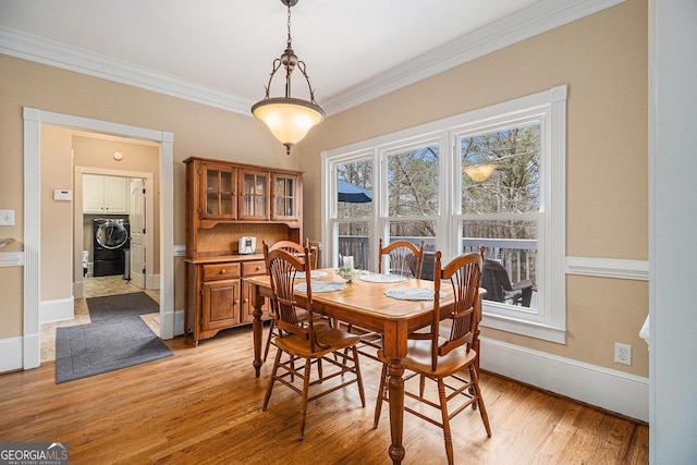 dining area featuring ornamental molding, light wood-style flooring, and baseboards