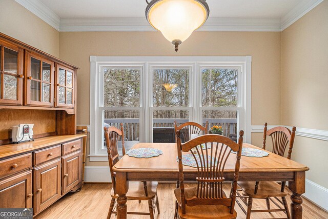 dining area with light wood-style floors, ornamental molding, and baseboards