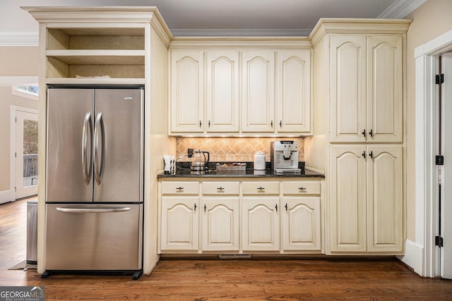 kitchen with dark countertops, dark wood-type flooring, cream cabinetry, and freestanding refrigerator