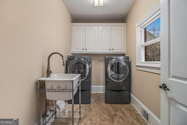 clothes washing area featuring visible vents, independent washer and dryer, cabinet space, and baseboards