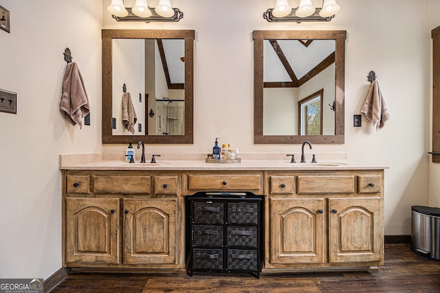 full bath with double vanity, baseboards, a sink, and wood finished floors