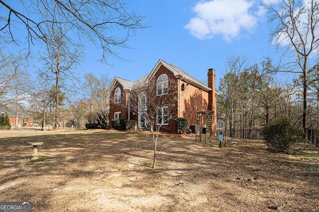 view of side of property featuring a chimney and brick siding