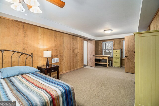 carpeted bedroom with visible vents, ceiling fan, and wooden walls