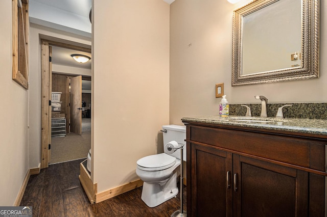 bathroom with vanity, wood finished floors, toilet, and baseboards