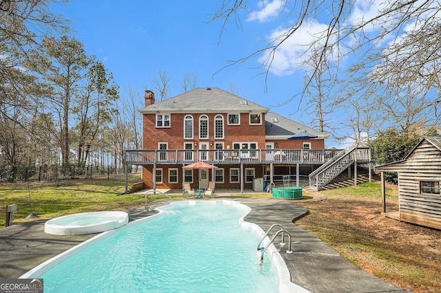 exterior space featuring a lawn, stairway, a wooden deck, and an in ground hot tub