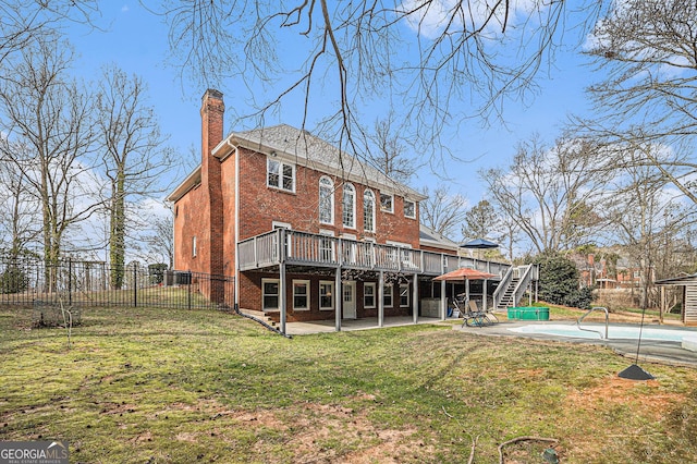 back of house with a lawn, a chimney, fence, a deck, and a patio area