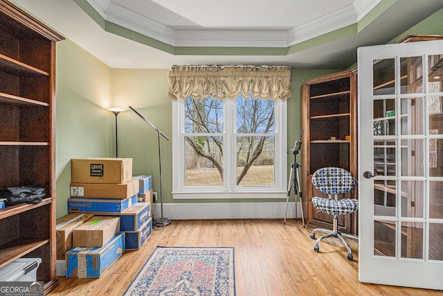 office space with wood finished floors, ornamental molding, a raised ceiling, and baseboards