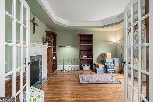 living area featuring a tray ceiling, french doors, wood finished floors, and crown molding