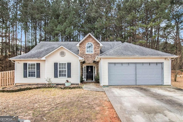 view of front of property with a garage, driveway, a shingled roof, and fence