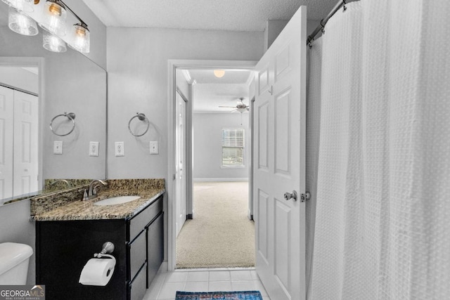 bathroom with tile patterned flooring, vanity, ceiling fan, toilet, and a textured ceiling