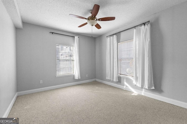 carpeted spare room with ceiling fan, a healthy amount of sunlight, and a textured ceiling