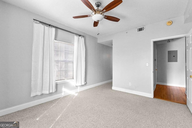 spare room featuring ceiling fan, carpet flooring, electric panel, and a textured ceiling