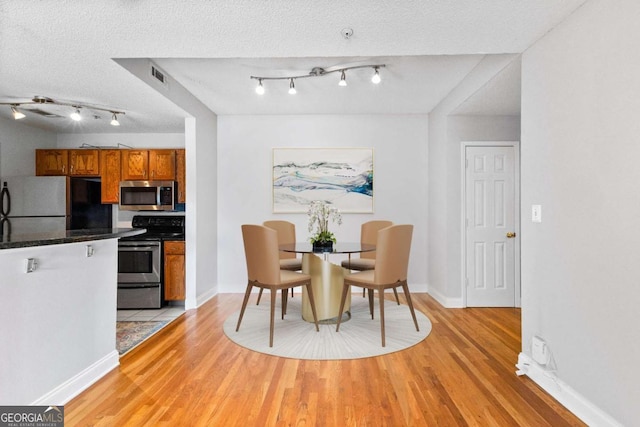 dining space featuring light hardwood / wood-style floors and a textured ceiling