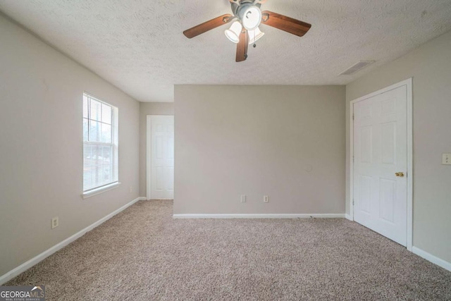 carpeted empty room with ceiling fan and a textured ceiling