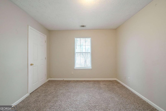 carpeted empty room featuring a textured ceiling