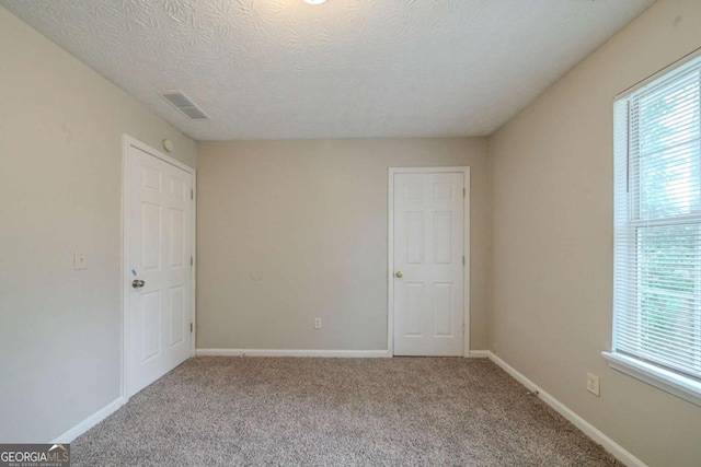 unfurnished bedroom with multiple windows, a textured ceiling, and carpet