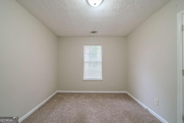 unfurnished room with carpet and a textured ceiling