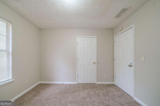 unfurnished bedroom featuring a textured ceiling and light carpet