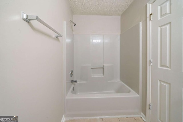 bathroom featuring a textured ceiling, shower / bathing tub combination, and tile patterned floors