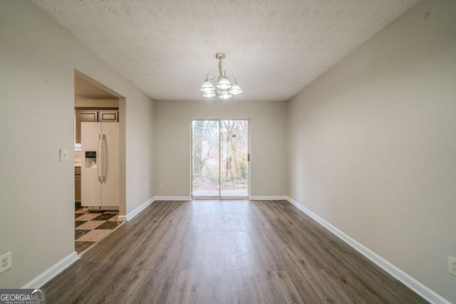 unfurnished dining area featuring a textured ceiling, dark hardwood / wood-style floors, and a notable chandelier