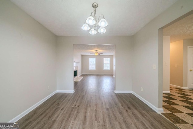 interior space with a textured ceiling, dark wood-type flooring, and ceiling fan with notable chandelier