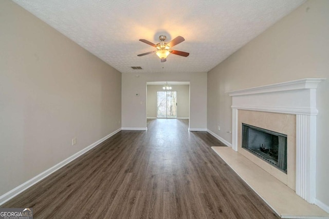 unfurnished living room featuring a fireplace, dark hardwood / wood-style floors, a textured ceiling, and ceiling fan with notable chandelier